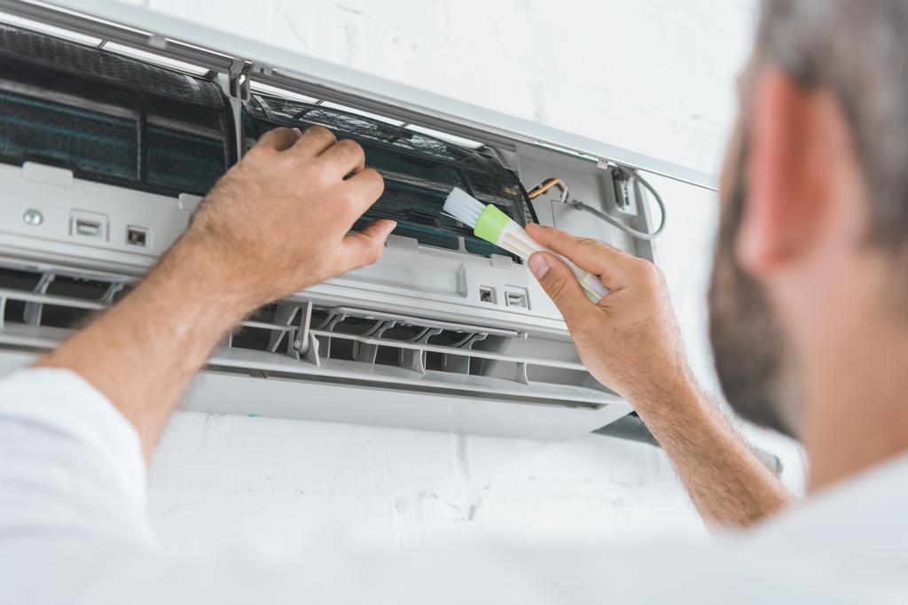 selektiver Fokus der Reparaturfirma, die Klimaanlage mit Bürste reinigt - Foto, Bild