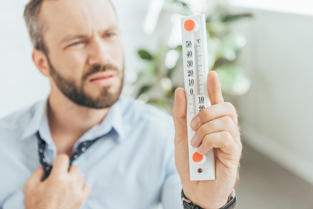 selective focus of businessman in hot office looking at thermometer - Photo, Image