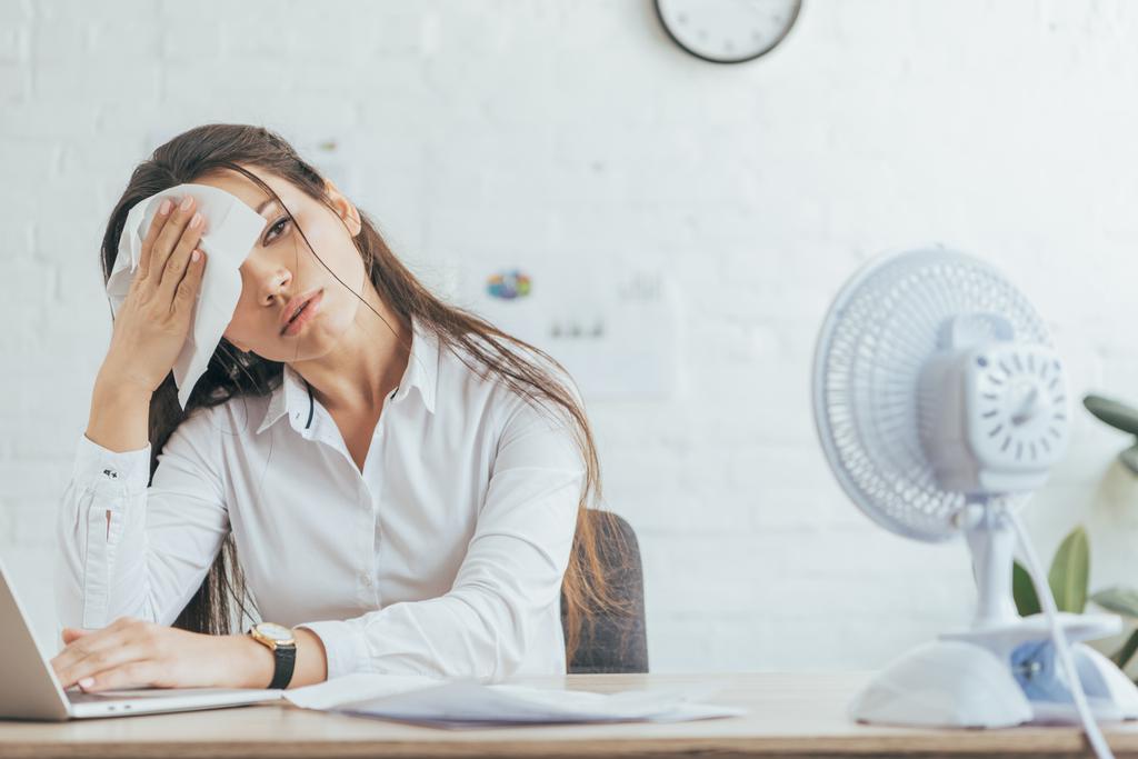 потная деловая женщина, работающая в офисе с электрическим вентилятором
  - Фото, изображение