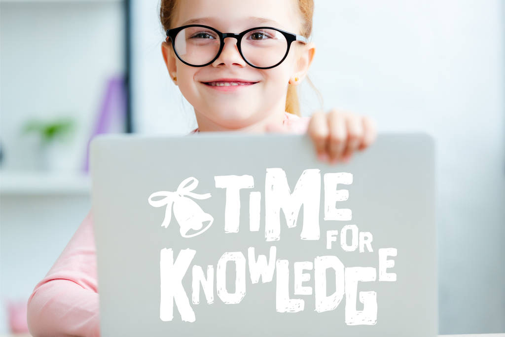 Schattige rode haired schoolmeisje in brillen laptop met "t─│d voor kennis" belettering - Foto, afbeelding