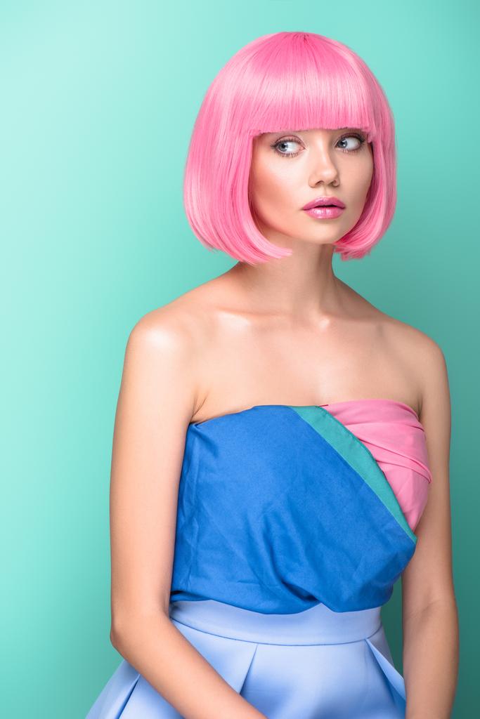 beautiful young woman with pink bob cut and dress looking away isolated on turquoise - Photo, Image