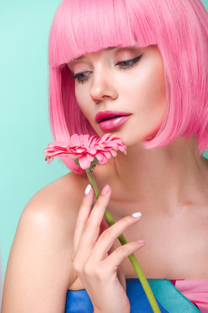 mooie jonge vrouw met roze bob gesneden bedrijf bloem geïsoleerd op turquoise - Foto, afbeelding