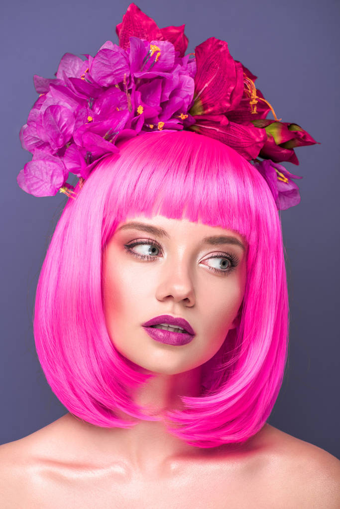 atraktivní mladá žena s růžové bob střih a květiny do vlasů při pohledu od izolovaných na fialové - Fotografie, Obrázek