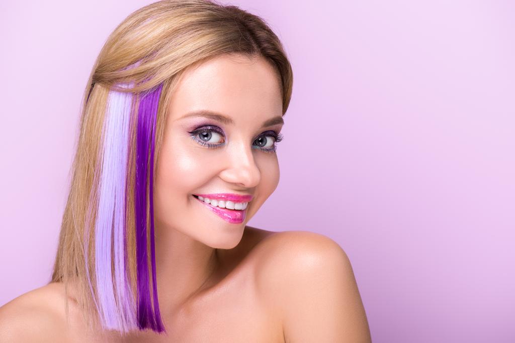 close-up portrait of happy young woman with stylish makeup and purple hair strands isolated on purple - Photo, Image