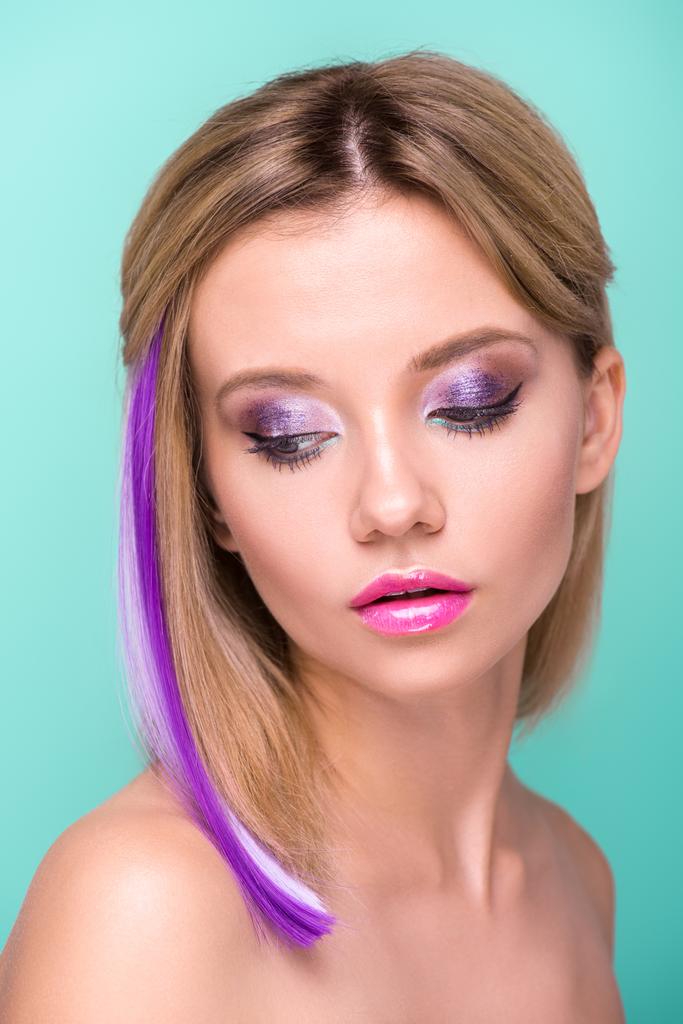 Nahaufnahme Porträt einer attraktiven jungen Frau mit stilvollem Make-up und lila Haarsträhne isoliert auf blau - Foto, Bild