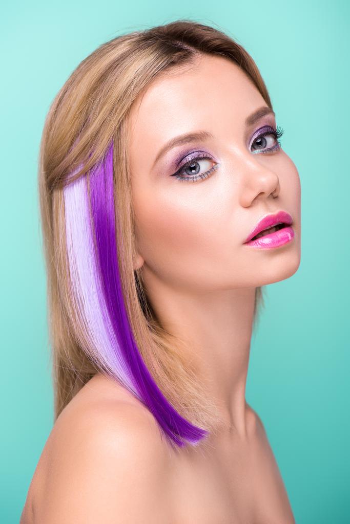 atractiva mujer joven con cabello encorvado con hebras púrpuras mirando a la cámara aislada en azul
 - Foto, Imagen