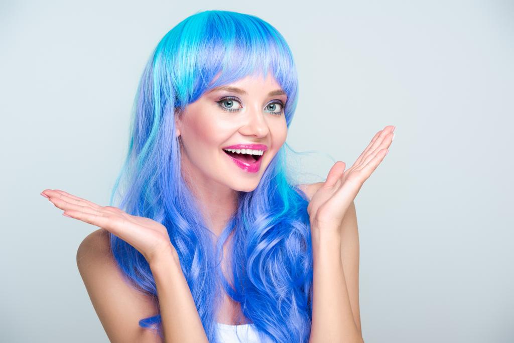 aufgeregte junge Frau mit leuchtend blauen Haaren vereinzelt auf grau - Foto, Bild