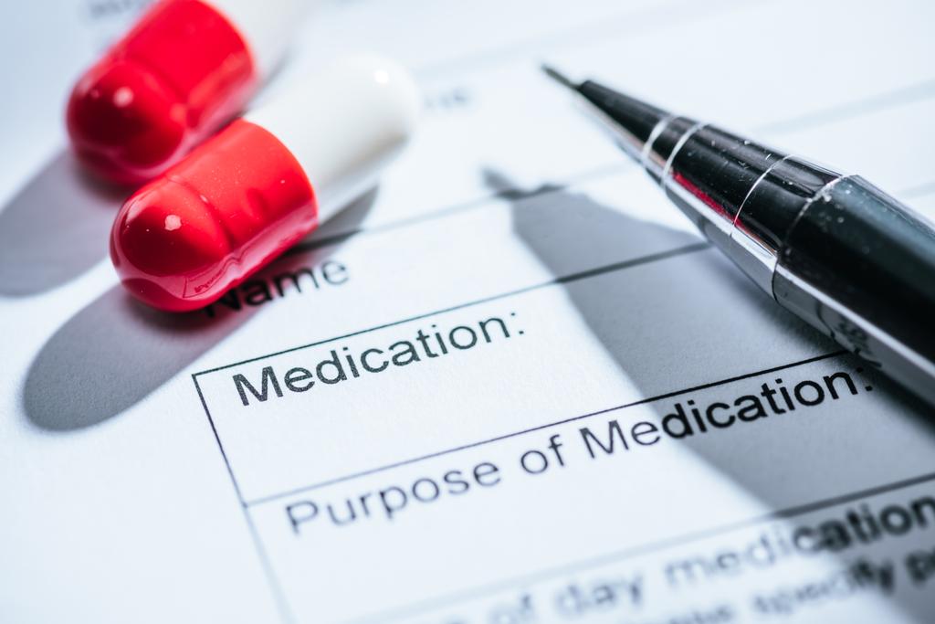Close-up van medische vragenlijst, rode pillen en op tafel  - Foto, afbeelding
