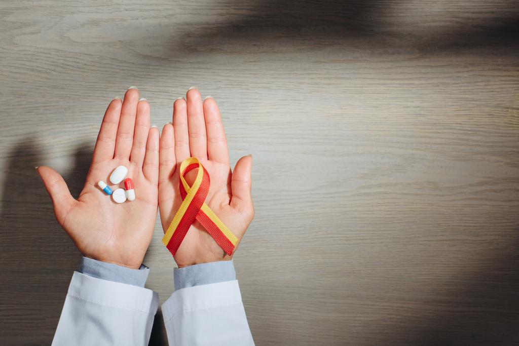 partial view of female doctor holding ribbon and pills, world hepatitis day concept - Photo, Image