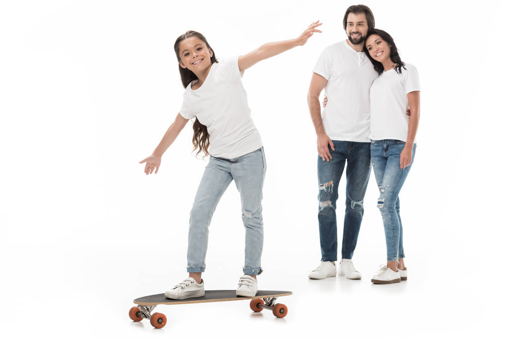 lachende ouders kijken naar dochter schaatsen op skateboard geïsoleerd op wit - Foto, afbeelding