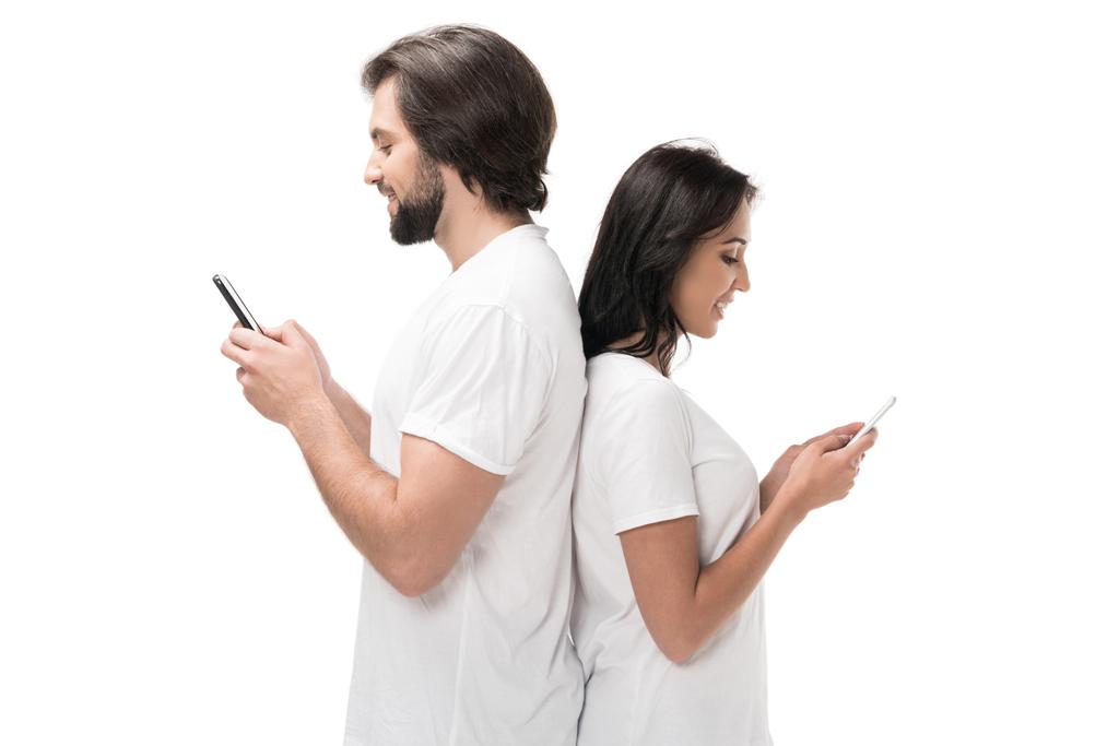 vista lateral de la pareja utilizando teléfonos inteligentes aislados en blanco
 - Foto, imagen