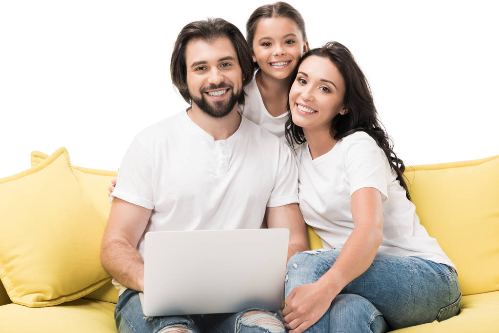 Portret van lachende gezin met laptop op gele sofa geïsoleerd op wit - Foto, afbeelding