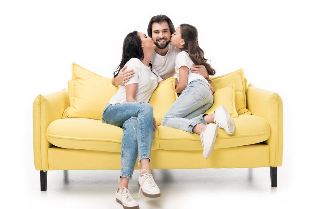 madre e figlia su divano giallo baciare felice padre isolato su bianco
 - Foto, immagini