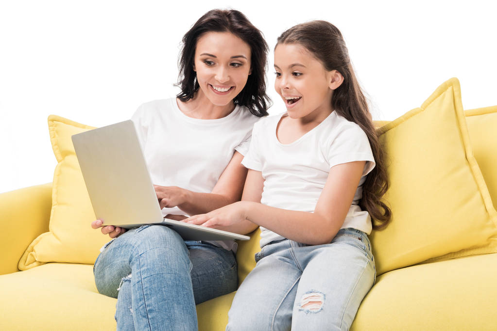 Portret van de moeder en gelukkige dochter met behulp van de laptop samen op sofa geïsoleerd op wit - Foto, afbeelding