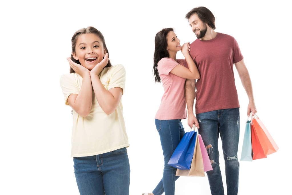 selectieve aandacht van opgewonden kind en ouders met boodschappentassen achter geïsoleerd op wit - Foto, afbeelding