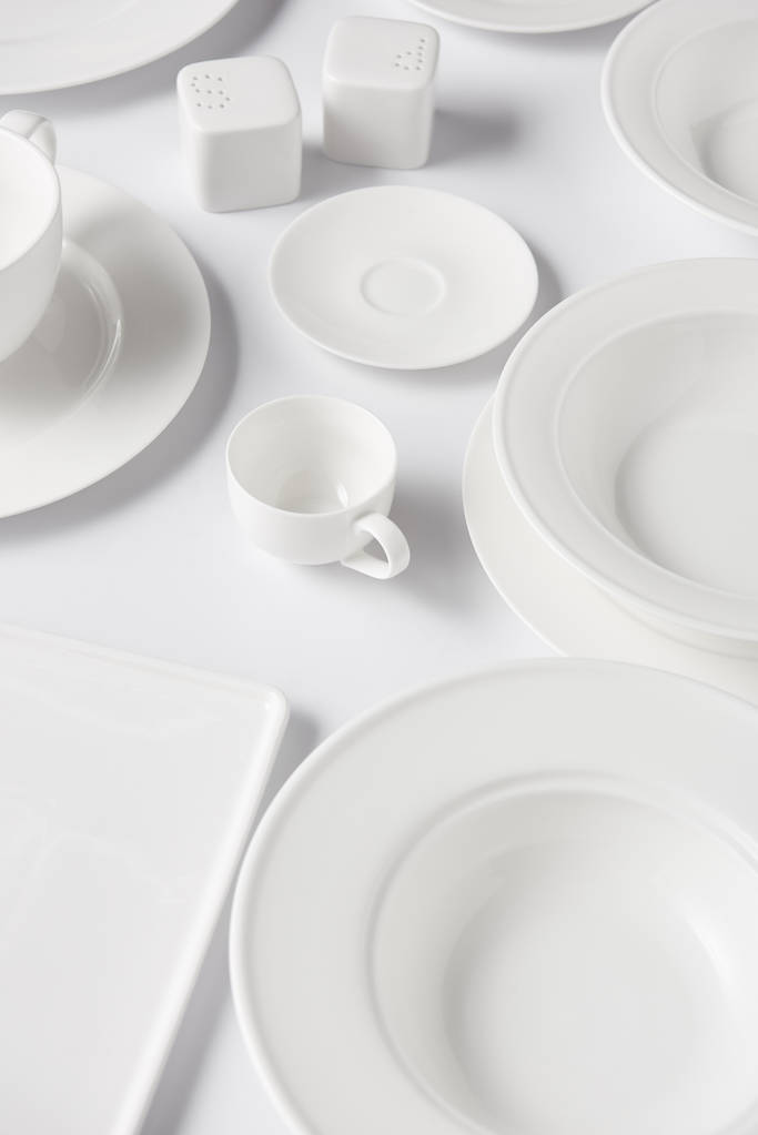 vue grand angle de différentes assiettes, tasses, salière et poivrière sur table blanche
  - Photo, image