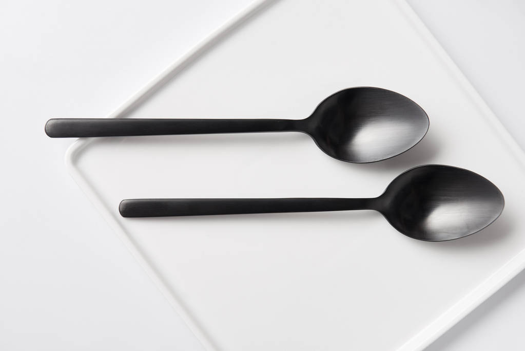 vista superior de dos cucharas y plato en mesa blanca, concepto minimalista
 - Foto, Imagen