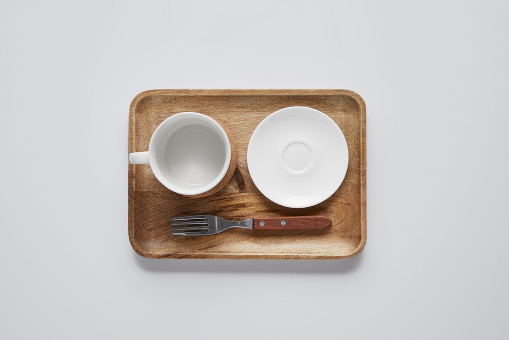 top view of wooden tray with plate, bowl and fork on white table, minimalistic concept - Photo, Image