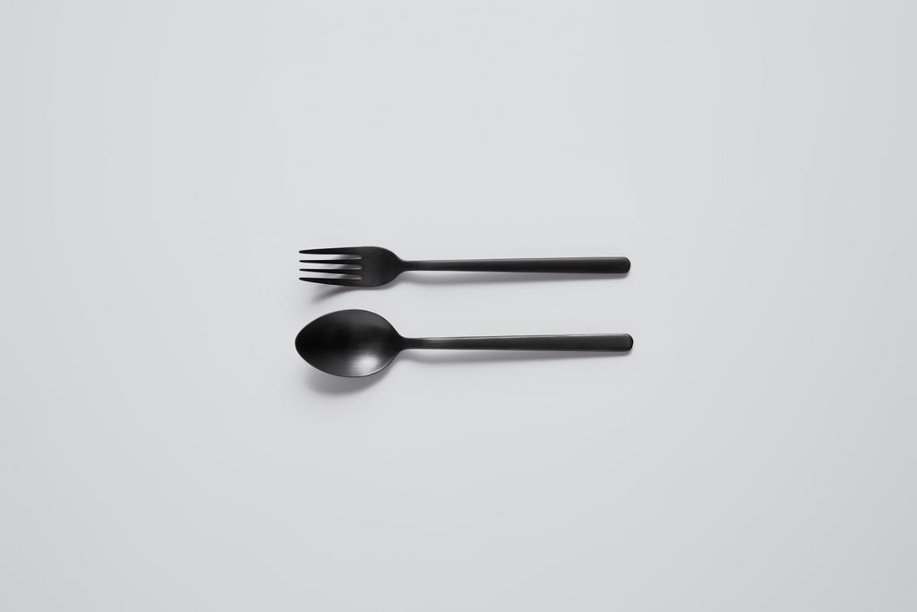Widok z góry czarny łyżka i widelec na biały stół, minimalistycznym koncepcji - Zdjęcie, obraz