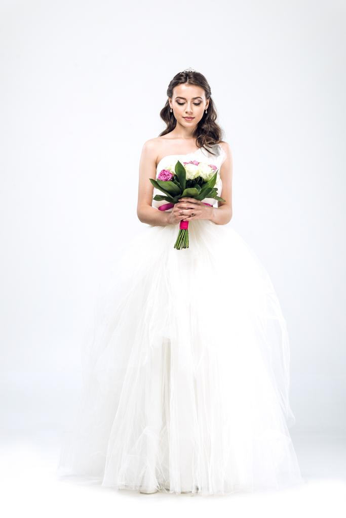 schöne junge Braut im Brautkleid mit Strauß auf weißem Grund - Foto, Bild