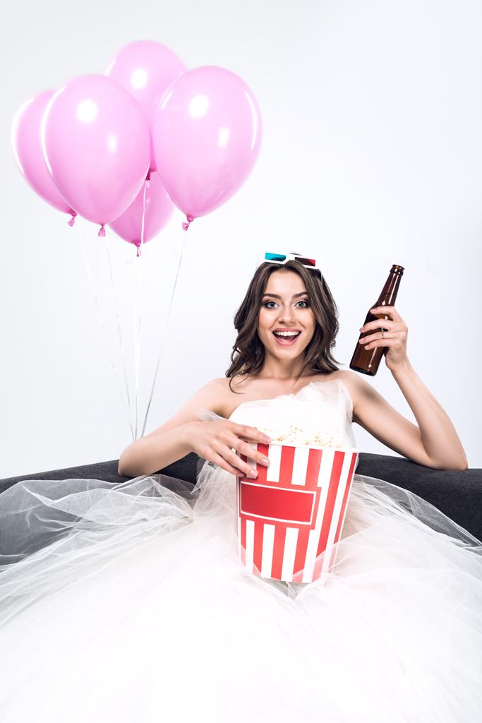 happy young bride in wedding dress with beer and bucket of popcorn watching movie isolated on white - Photo, Image