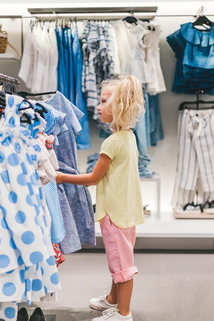vista laterale di adorabile bambino che sceglie i vestiti nel negozio
  - Foto, immagini