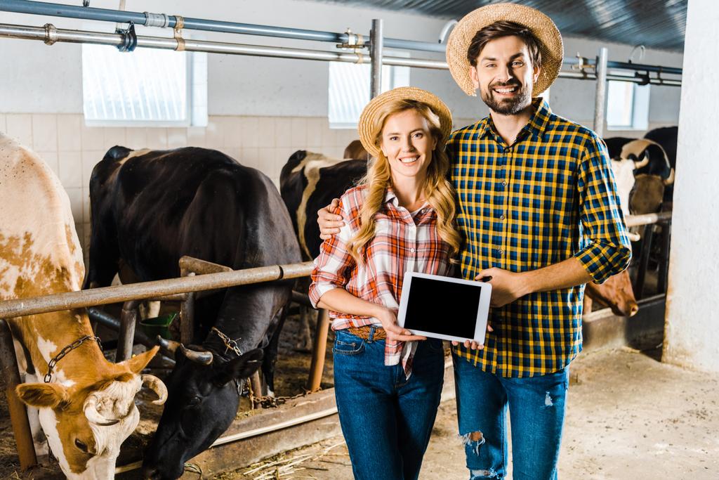lachende paar boeren houden tablet met leeg scherm in stal - Foto, afbeelding