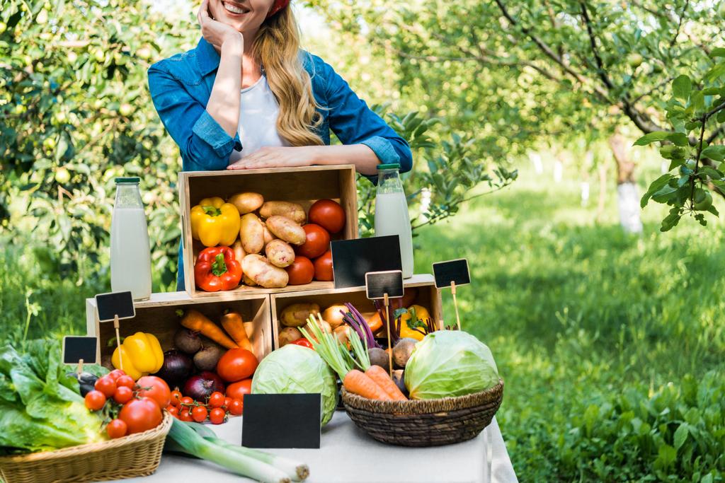 обрезанное изображение фермера, опирающегося на коробки с овощами на фермерском рынке
  - Фото, изображение