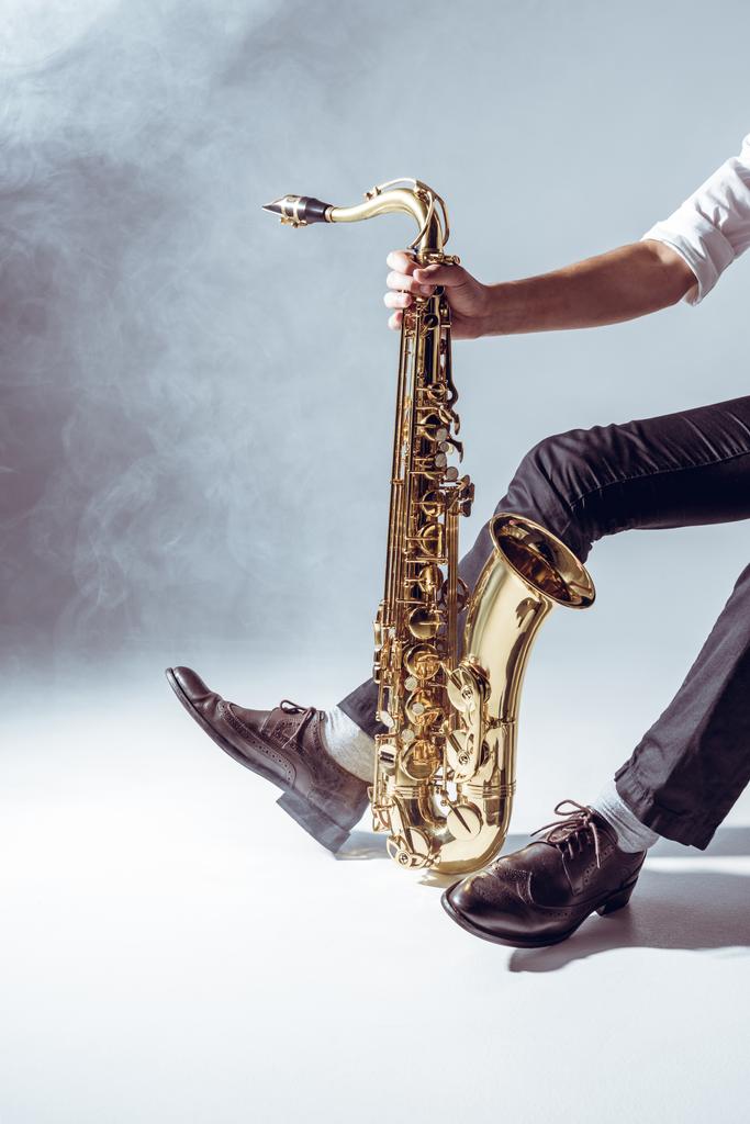 Oříznout záběr profesionálních mladý hudebník drží saxofon Grey - Fotografie, Obrázek