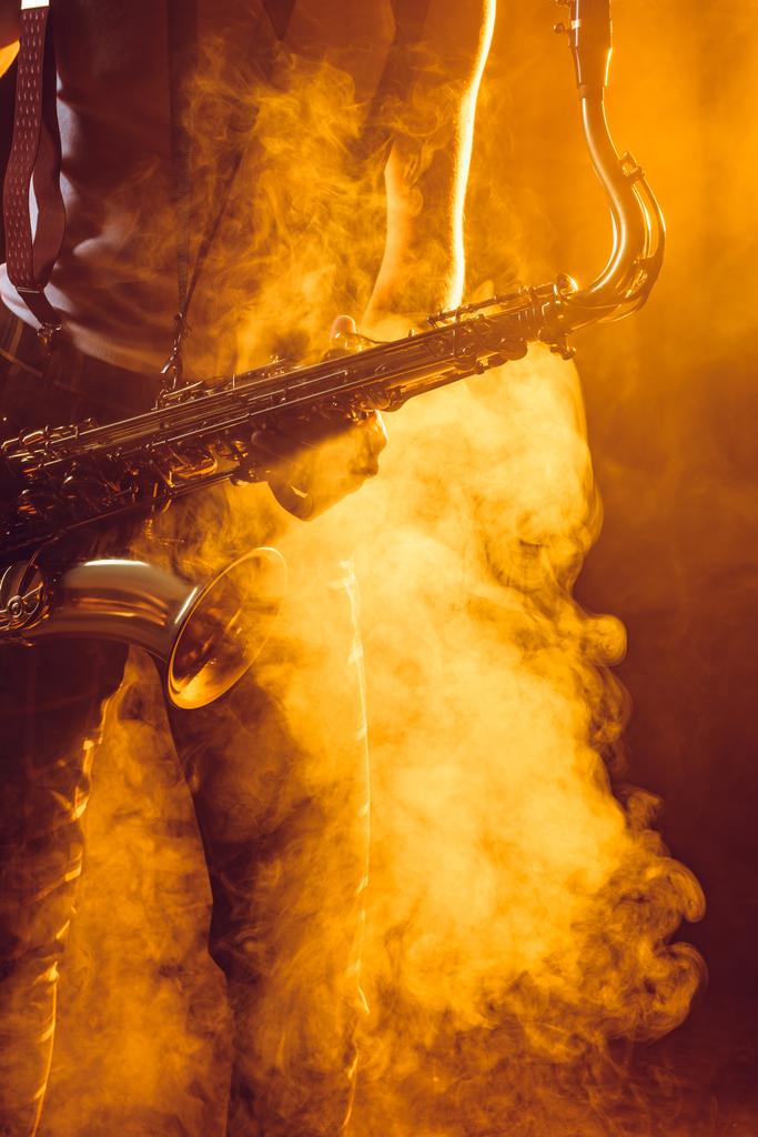 plan recadré d'un jeune musicien tenant un saxophone en fumée
  - Photo, image