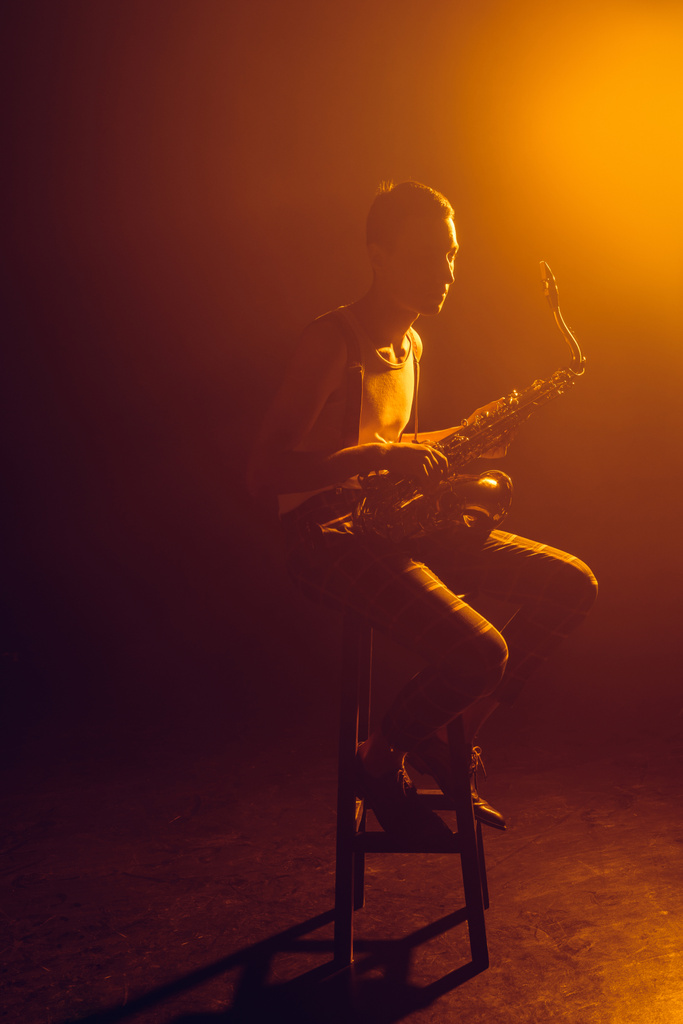 taburede oturan ve saksafon tutan genç şık jazzman - Fotoğraf, Görsel