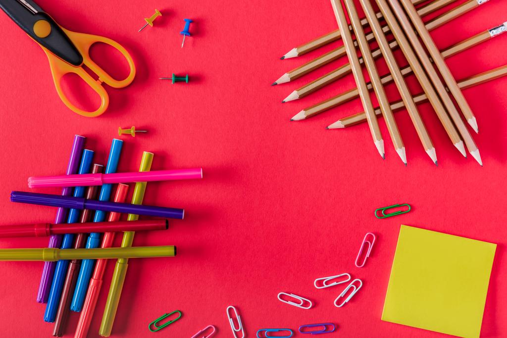 pohled shora barevné značky, nůžky, špendlíky, sponky, držet jej a tužky na červeném pozadí  - Fotografie, Obrázek
