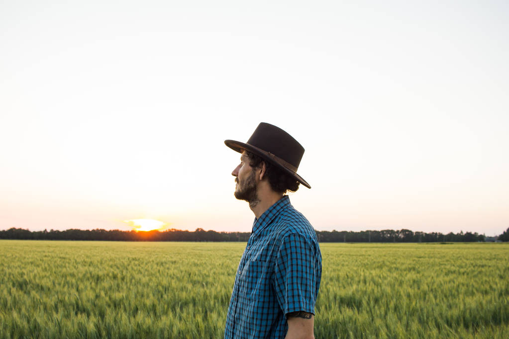 若い男性農家単独で麦畑で日没時に  - 写真・画像