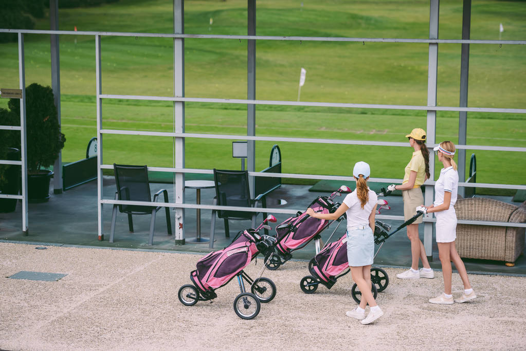 Seitenansicht von Golferinnen mit Golfausrüstung am Golfplatz am Sommertag - Foto, Bild