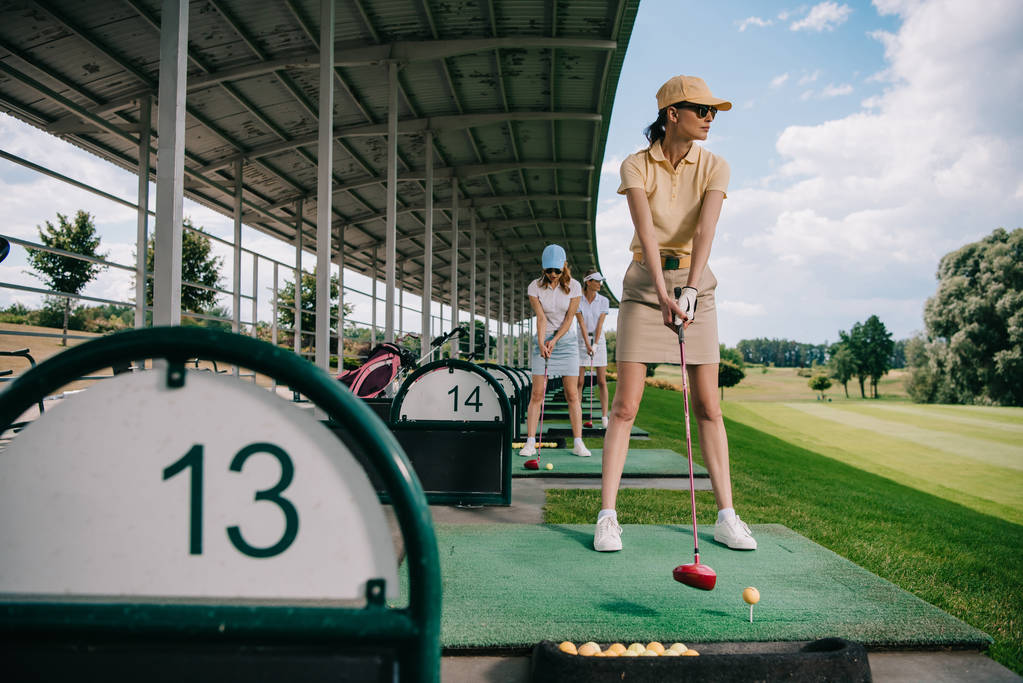femmes en casquettes avec des clubs de golf jouant au golf sur le terrain de golf
 - Photo, image