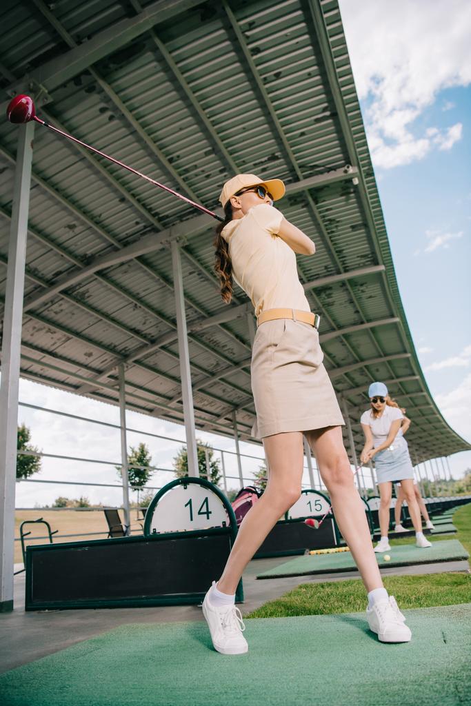 matala kulma näkymä naisten golfmailat pelaa golfia golfkentällä
 - Valokuva, kuva