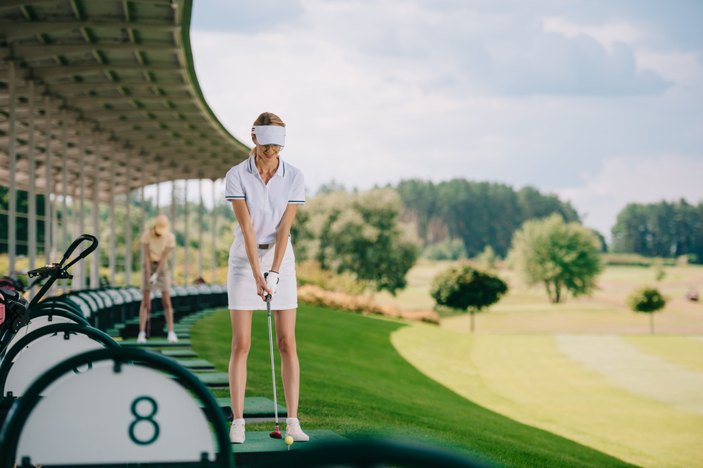 valikoiva painopiste hymyilevä naisten golfaaja poolossa ja korkki golfmailalla golfkentällä
 - Valokuva, kuva