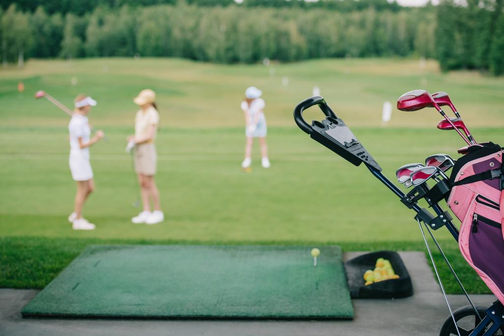 selective focus of golf gear and women in caps at golf course - Photo, Image