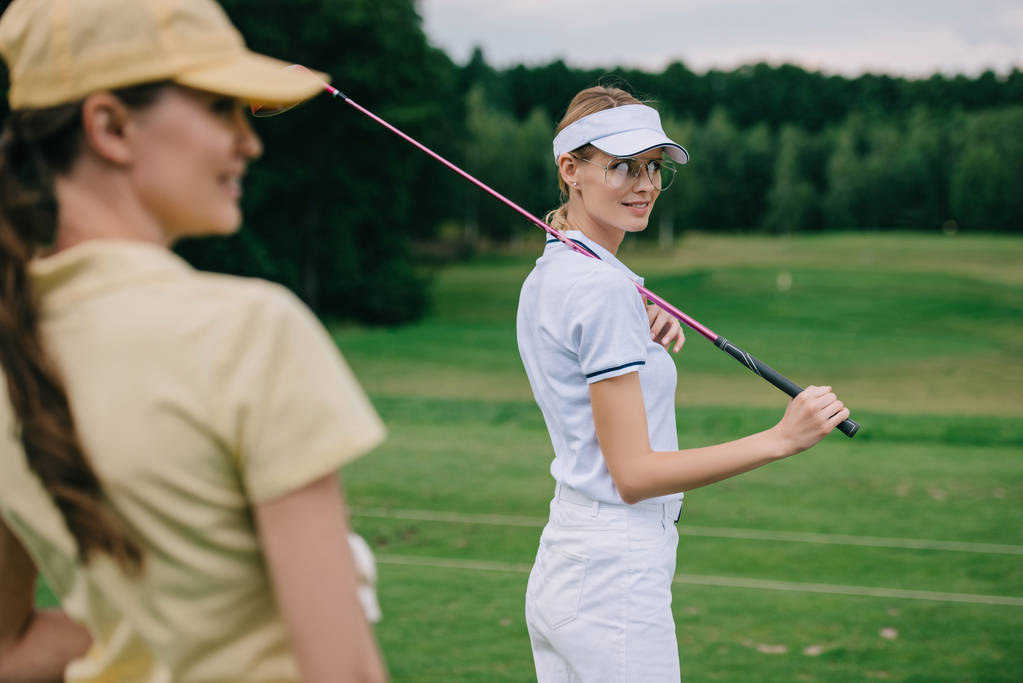 Kadınlar kapaklar golf sahasında golf ekipmanları ile gülümseyen seçici odak - Fotoğraf, Görsel