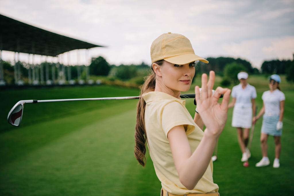 Избирательный фокус женщины-гольфиста с клюшкой, показывающей знак ОК на поле для гольфа
 - Фото, изображение