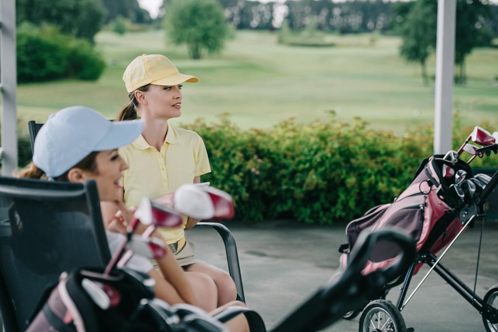 вид збоку жінки в шапках, що відпочивають після гри в гольф на полі для гольфу
 - Фото, зображення
