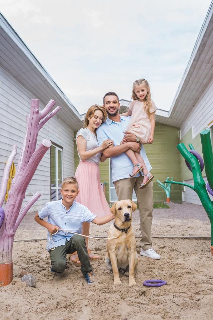 счастливые родители и дети, стоящие с приёмной собакой-лабрадором в приюте для животных
 - Фото, изображение