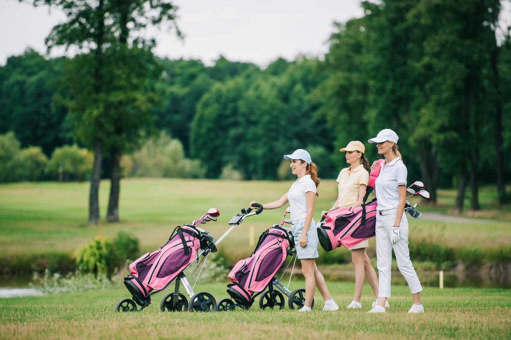 side view of female golf players in caps with golf equipment on golf course - Photo, Image
