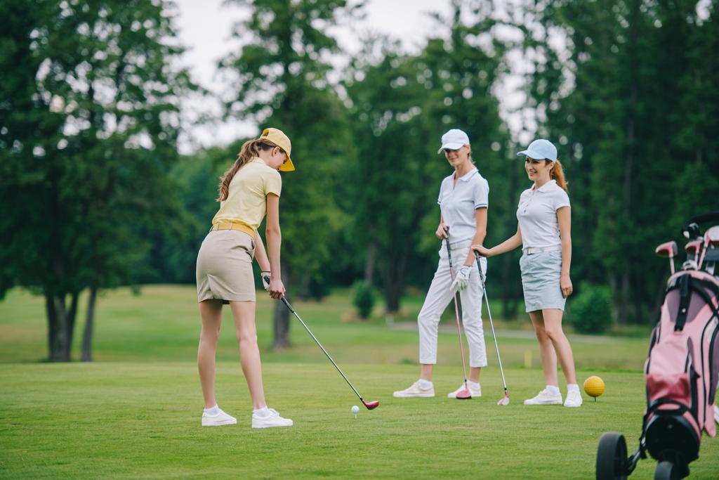 Kobieta w WPR, gry w golfa jednocześnie uśmiechając się przyjaciółmi, stojących w pobliżu pola golfowego - Zdjęcie, obraz