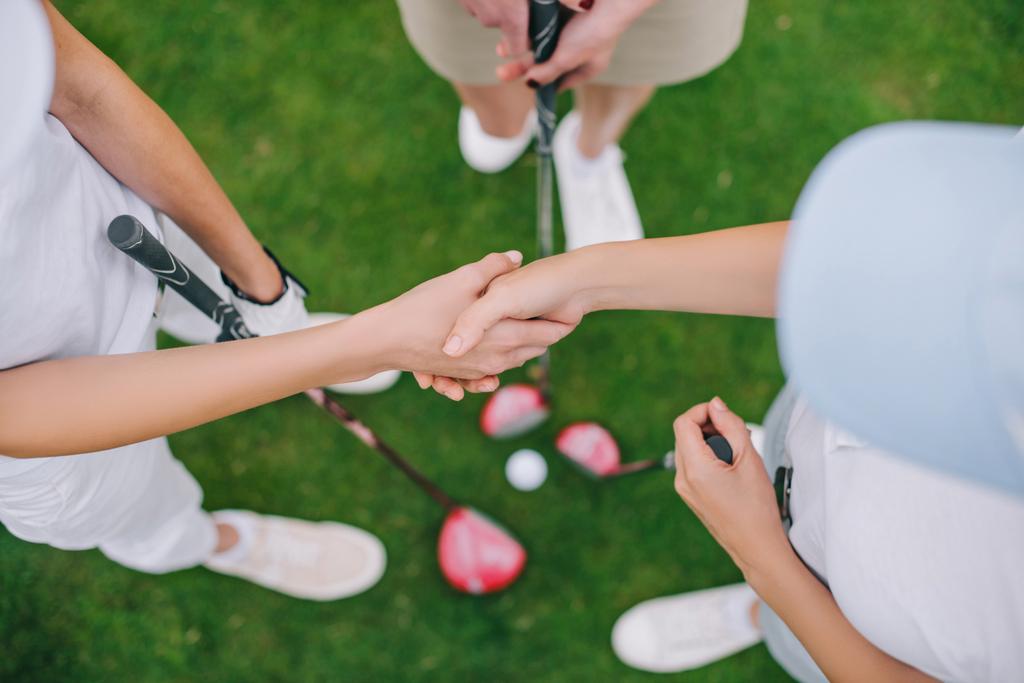 női golf játékosok a golf klubok kezet állt, míg a zöld gyep felülnézete - Fotó, kép