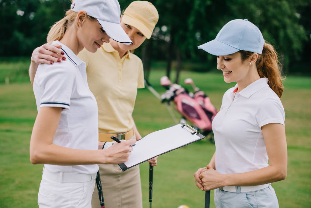 parceiros de negócios do sexo feminino com bloco de notas discutindo projeto durante jogo de golfe no campo de golfe
 - Foto, Imagem