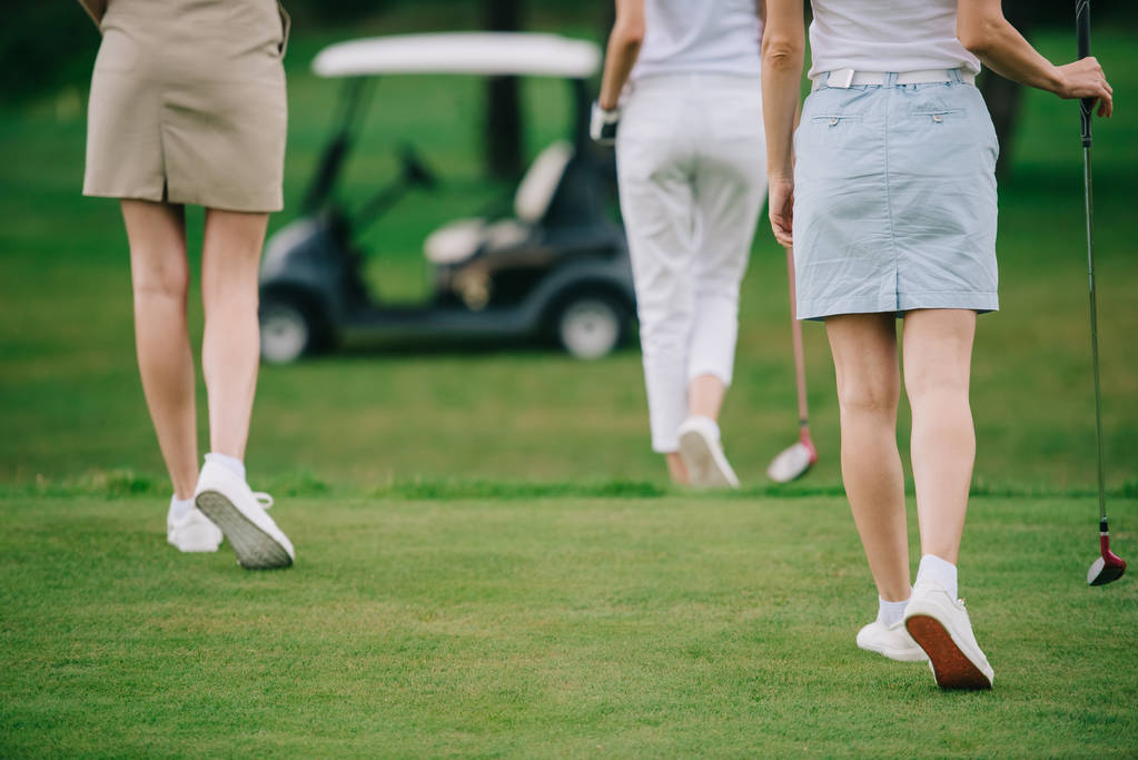 ゴルフクラブ ゴルフコースで緑の芝生の上を歩く女性のショットをトリミング - 写真・画像