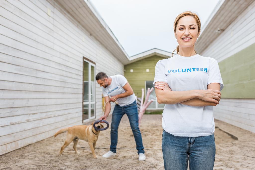 volunteer of animals shelter playing with labrador dog, woman looking at camera - Photo, Image