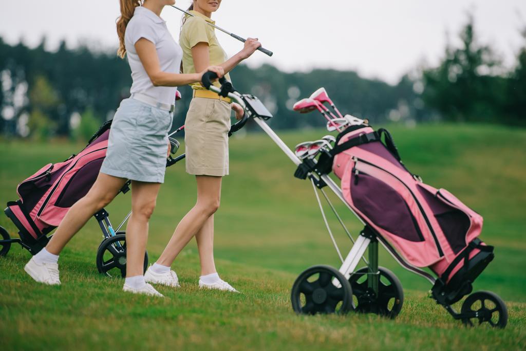 visão parcial de jogadores de golfe do sexo feminino em pólos andando no campo de golfe
 - Foto, Imagem