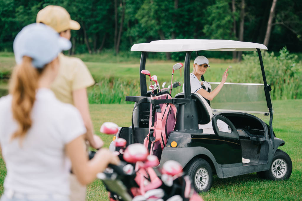 valikoiva painopiste naisen golf cart tervehdys ystäviä golfkentällä
 - Valokuva, kuva